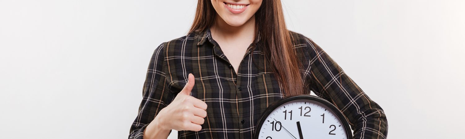 Smiling Woman in shirt holding the clock in hand and pointing at their
